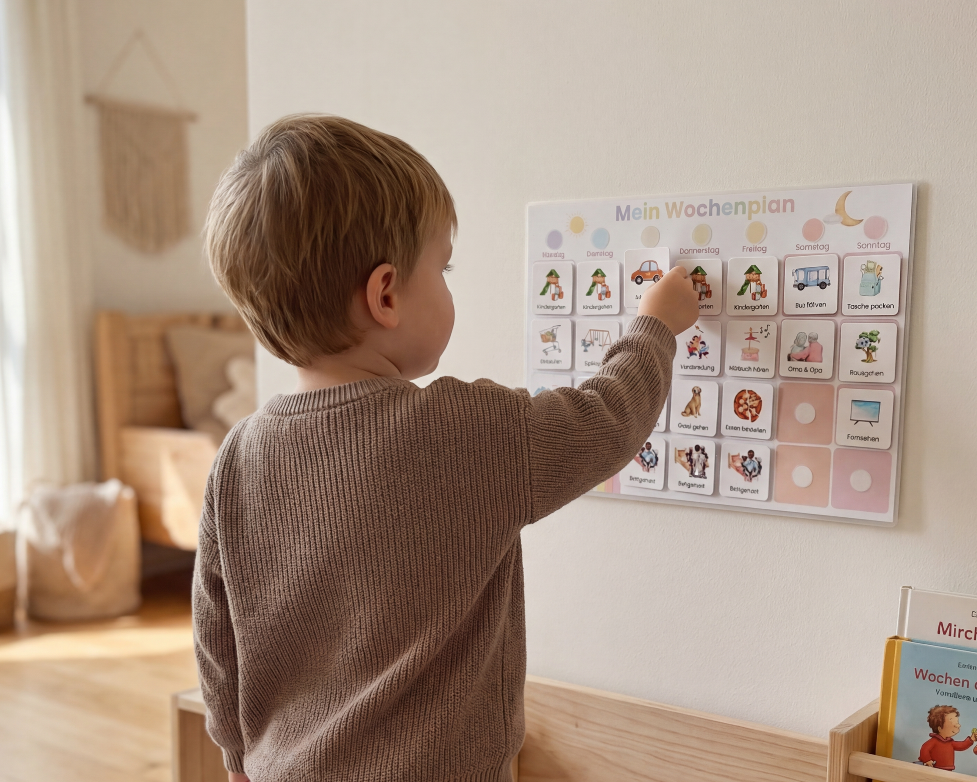 Junge klebt Symbolkarte auf Montessori Wochenplan an der Wand, fördert Selbstständigkeit und gibt Kindern Orientierung im Alltag